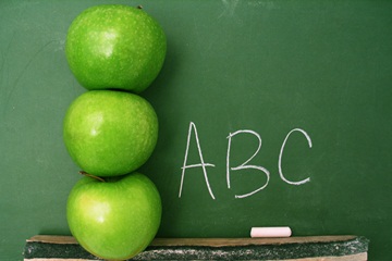 a picture of apples stacked in front of a chalkboard.